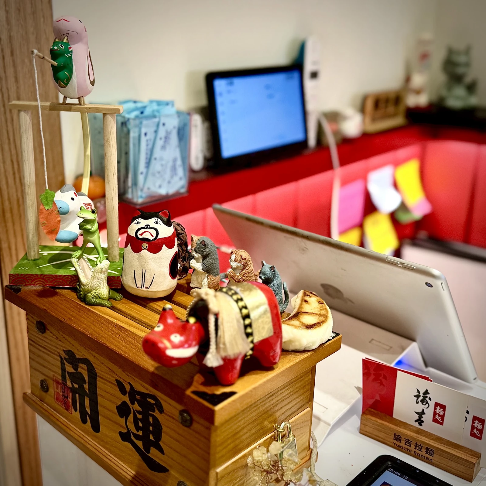 諭吉拉麵櫃檯上的日式小擺飾、木製賽錢箱與品牌名片